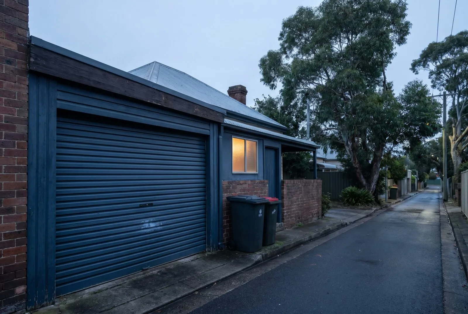 A tight single-car garage with a corrugated roller door on an older cottage in Adamstown